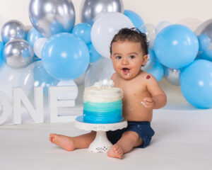 One year old Baby photographed with balloons and a cake during a first birthday cake smash photoshoot