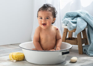 A one year old baby taking a bath in a metal tub during a photoshoot at Life in Pink Photography in Janesville, Wisconsin 