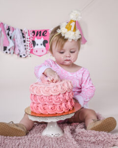 First Birthday Cake smash of a little girl with a pink cake taken in our Janesville area photography studio