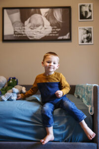 Big Brother sitting on a bed in his room as he waits for his new little brother