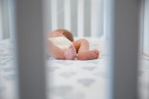 Newborn baby photographed through the slates in his crib