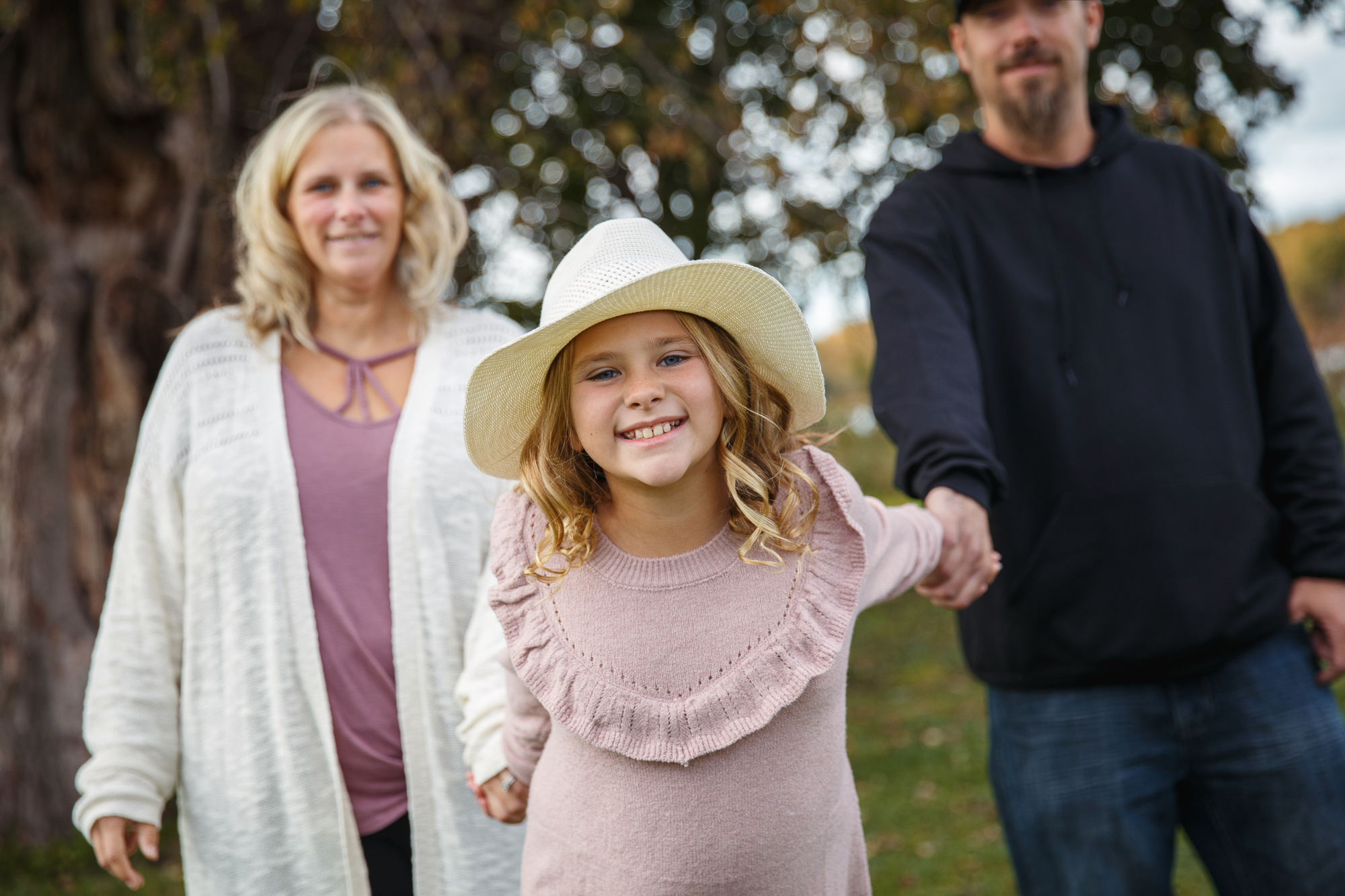 A photo of a girl wearing a hat with her parents taken during a photo mini session