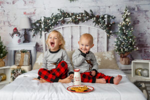 Image of two brothers aged one and two sitting on a bed with milk and cookies