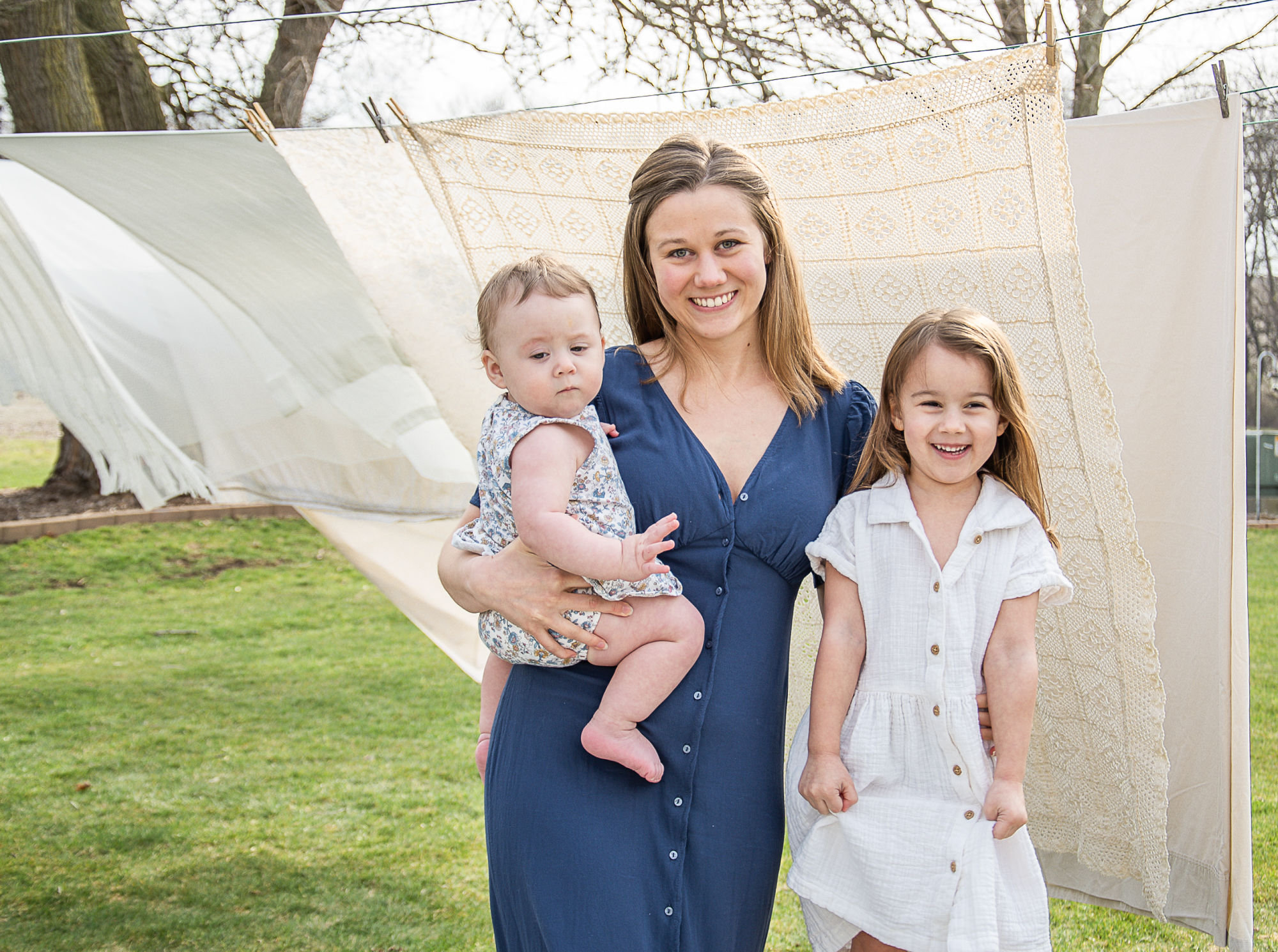Image of a mom with a baby and little girl taken outdoors with a clothesline