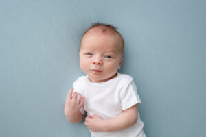 Newborn Photos of a baby boy wearing a white t-shirt, laying on a blue blanket