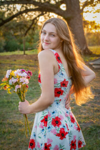 Teenage girl with sun in her hair and holding some flowers