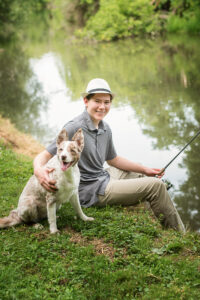 Boy fishing with his dog as a prop in his senior photos.