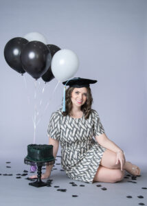 Graduate student celebrating her master degree with balloons and a cake
