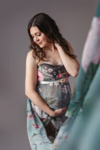 photo of a woman with a flowing floral dress during a maternity photo session with Life in Pink Photography