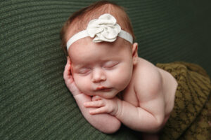 Newborn sleeping on a green blanket