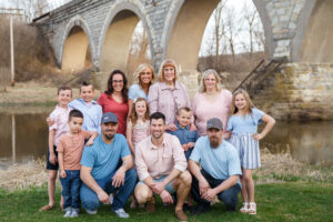 A stress-free family photo session of a Large extended family portrait taken outdoors near an arched bridge