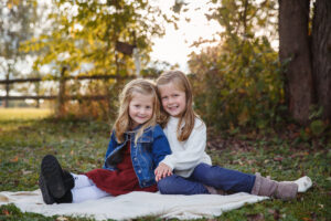 Sisters sitting on a blanket at a family photo session in Janesville