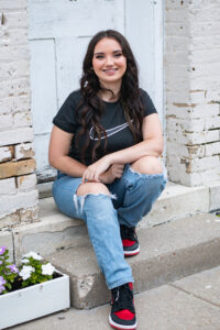 Portrait of a seventeen year old girl sitting on the step outside of a door. 