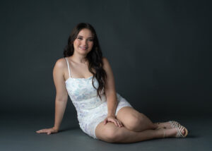 Studio portrait of a high school senior wearing a white dress.