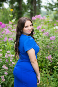 Cute teen girl wearing a blue dress in a feild of wild flowers.