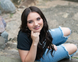 Senior Portrait of a teen girl wearing a black tshirt and jeans taken from above on stone steps. 