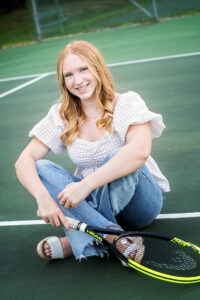 High school senior girl on the tennis court with her tennis racket.