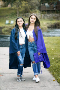 Cousins wearing blue cap and gown for senior portraits.