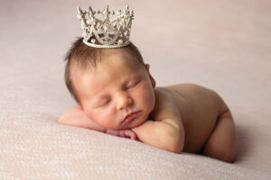 Portrait of a baby wearing a crown during a newborn session with Life in Pink Photography.