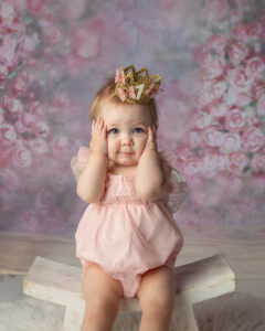 Cute close up of a little one year old girl wearing pink photographed on a floral background.