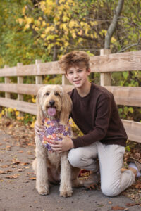 A portrait of a Teenage boy sitting outdoors with his dog ready for framing at Raven's Wish. 