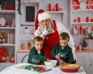 Photo of twin boys baking a pie with santa.