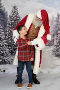 Santa picture of a boy in a plaid shirt interacting with Santa.