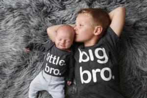 Portrait of a big brother and his little newborn brother with cute t-shirts saying Big Bro and Little Bro.