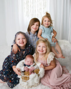 Family of siblings posed with newborn baby for professional photoshoot at Life in Pink Photography.