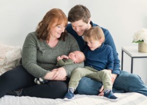 Family portrait of mom, dad, newborn baby and toddler son.