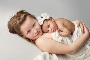 Lifestyle Image of a newborn baby girl with her big sister