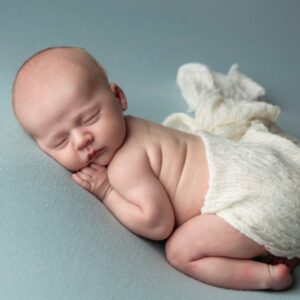 Newborn portraits of a sleeping on a blue blanket.