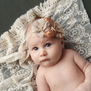 Portrait of a newborn baby girl laying on a lace blanket.