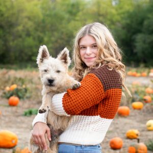Teen girl with her dog in a pumpkin field
