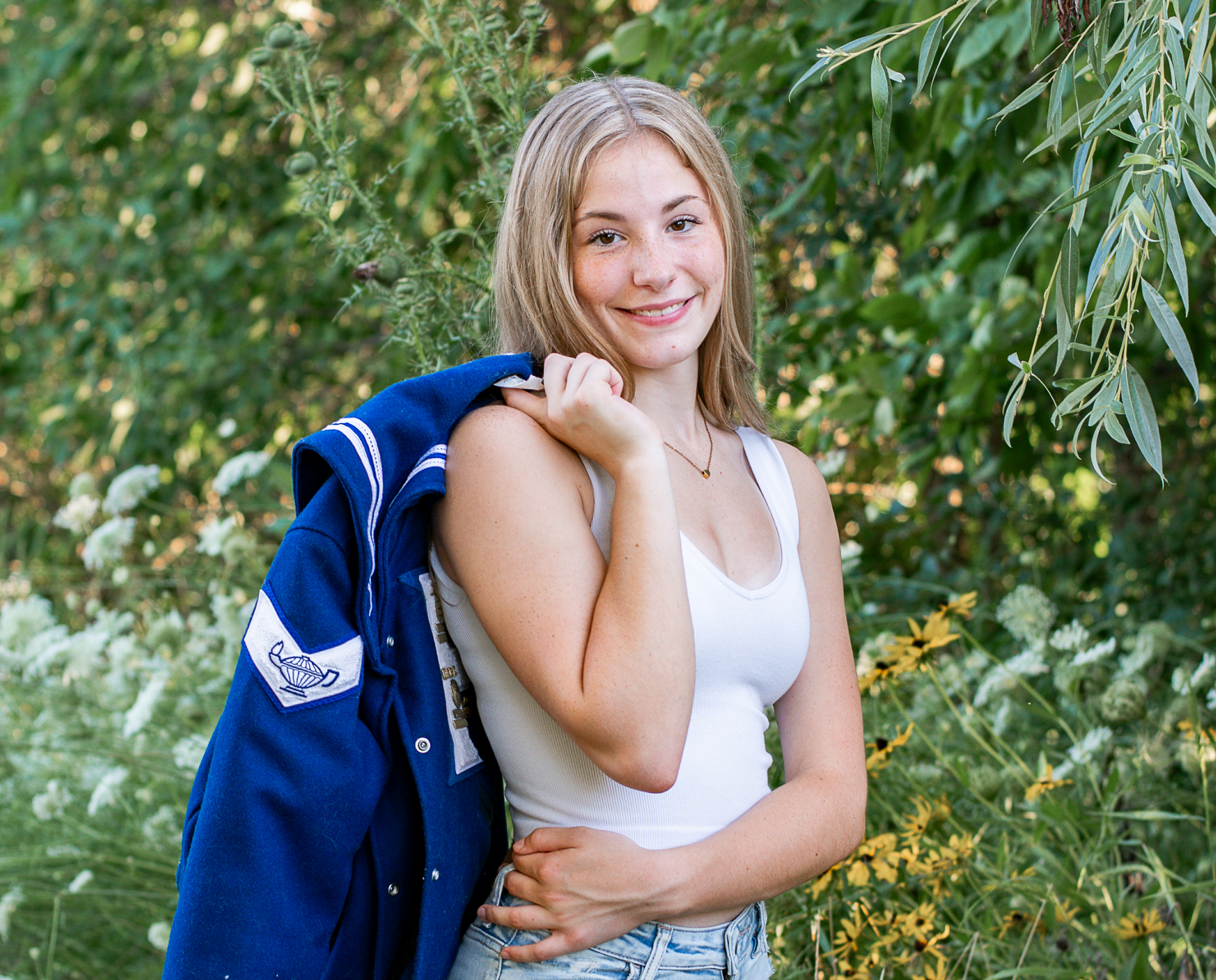 Senior pictures of High school girl holding her letterman's jacket.