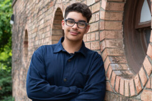 seventeen year old posing near a brick wall for senior portrait.