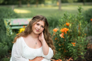 Senior portrait of a pretty girl in a white photographed at Beckman Mills in the flower garden.