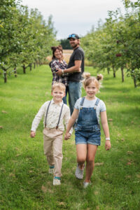 A picture of a family having fun in the apple orchard.